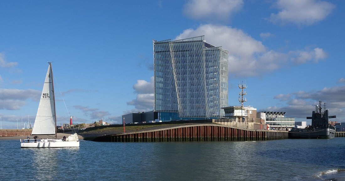 Die facettenreiche, mehrschichtig unterteilte Glasfassade des Inntel Hotel Den Haag Marina Beach erinnert an die Segel eines Bootes im Wind.